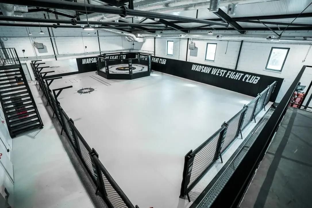 Biała mata podłogowa na całej sali treningowej Warsaw West Fight Club z klatką MMA i czarnymi matami ściennymi