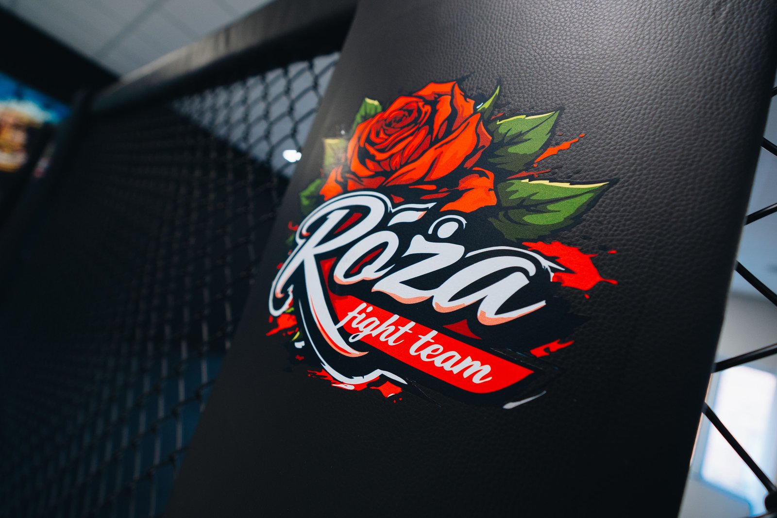 Zbliżenie logo Róża Fight Team nadrukowanego na czarnej osłonie słupa systemu Cage Wall.