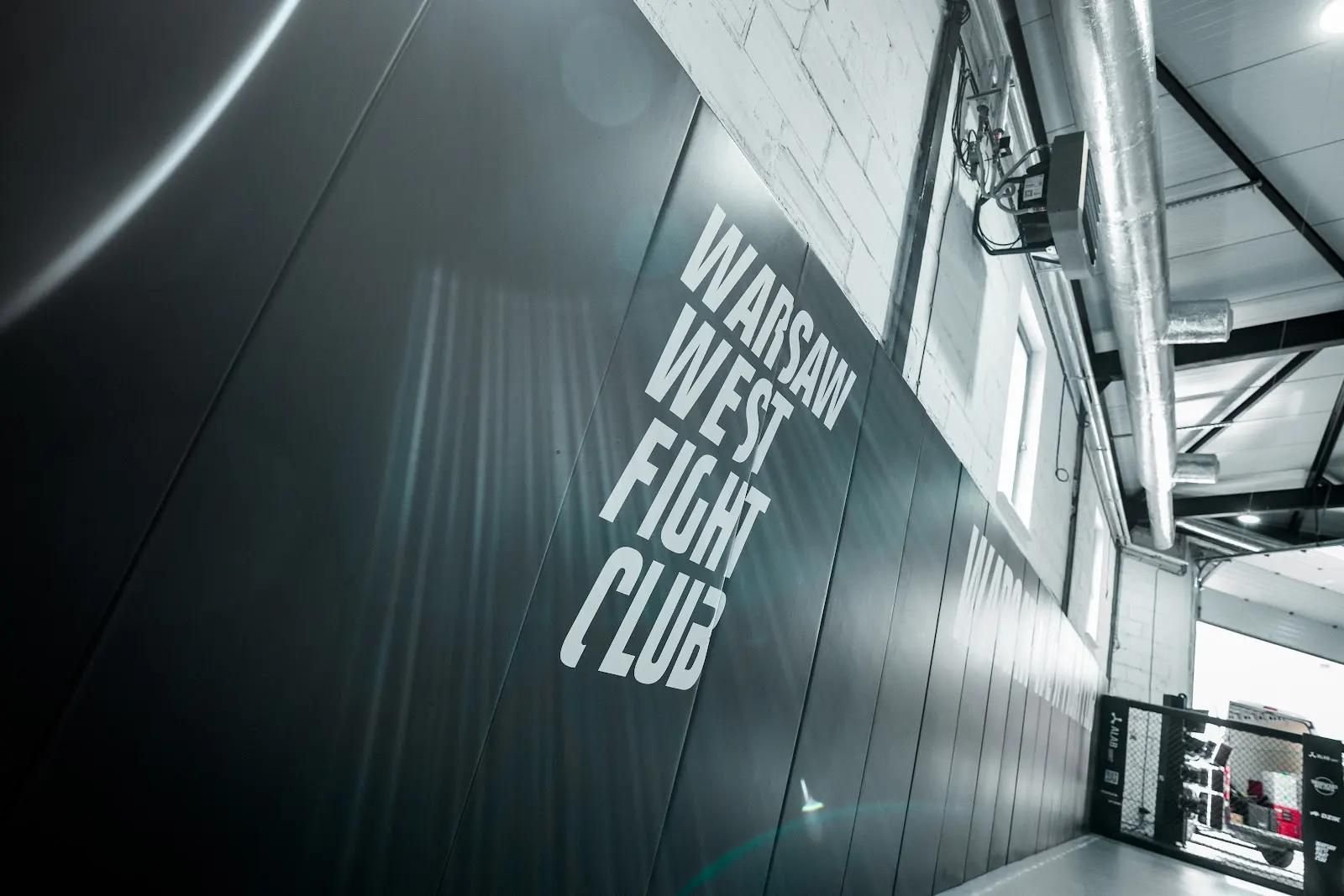 Zbliżenie na czarne maty ścienne z pionowym napisem Warsaw West Fight Club pod ceglaną ścianą
