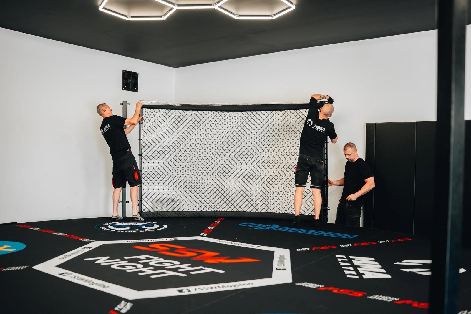 Mata podłogowa 4 cm z nadrukiem SSW Fight Night i elementami footwork, montaż siatki Cage Wall na ścianie