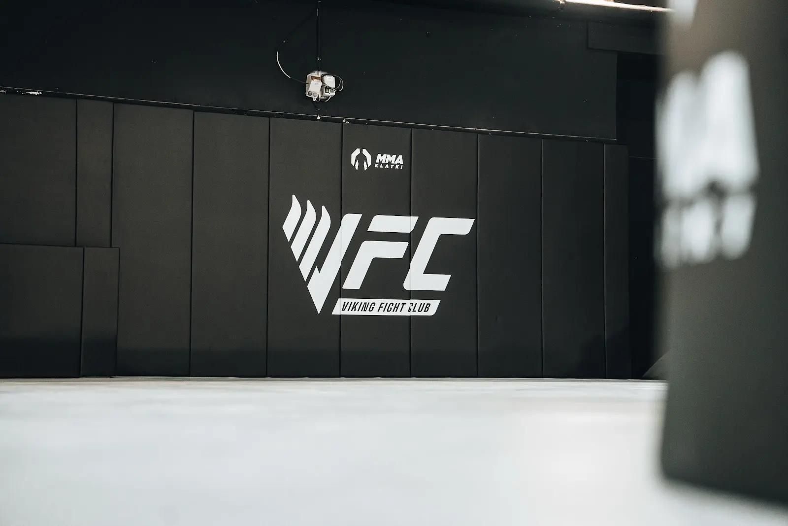 Czarne maty ścienne z logo Viking Fight Club, na pierwszym planie rozmyty worek treningowy