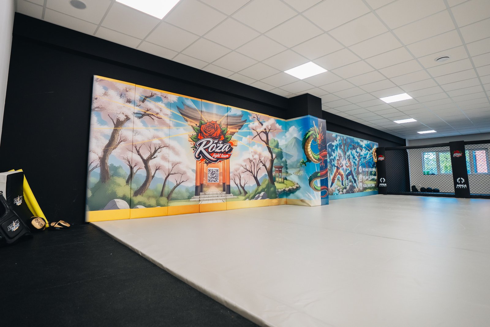 Mata podłogowa i personalizowane maty ścienne w sali Róża Fight Team. Grafika z japońskim motywem przechodzi na osłonięty filar obok Cage Wall.