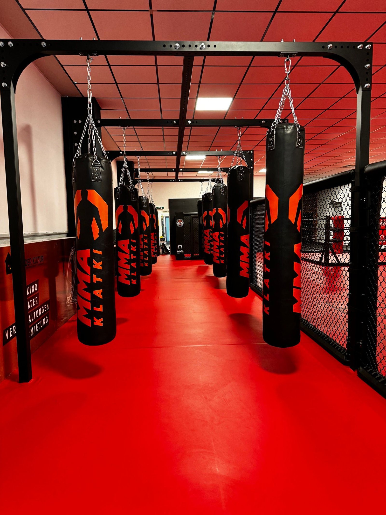 Strefa worków bokserskich wzdłuż czerwonej ściany klubu Fameless Fight Club