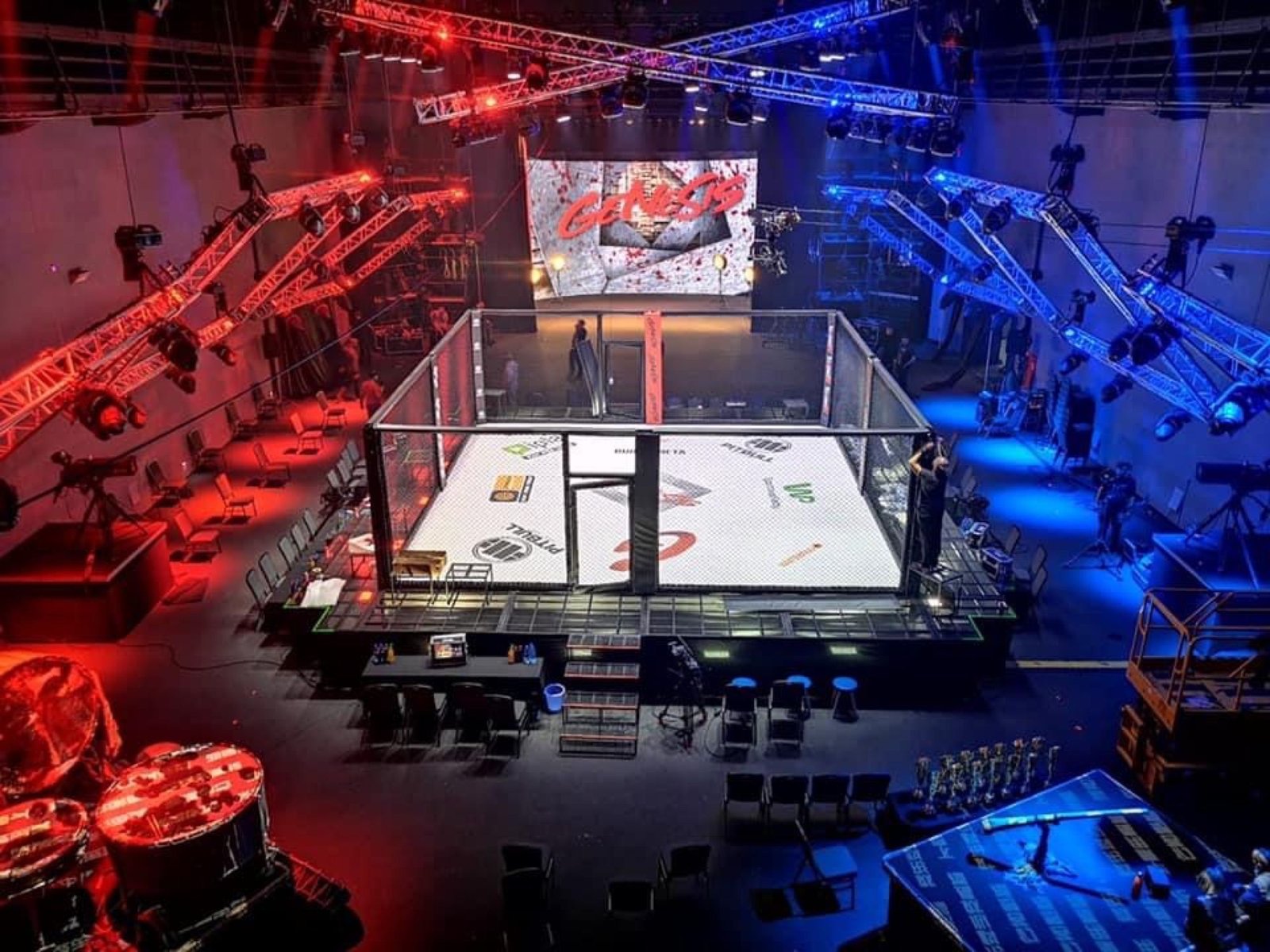 Kwadratowa klatka MMA na podeście podczas gali Genesis w oświetlonej hali