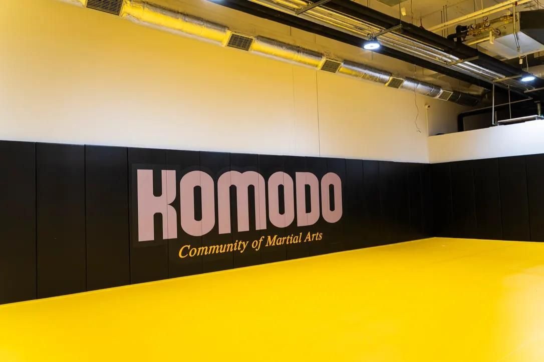 Czarne maty ścienne z różowym napisem Komodo Community of Martial Arts i żółta mata podłogowa