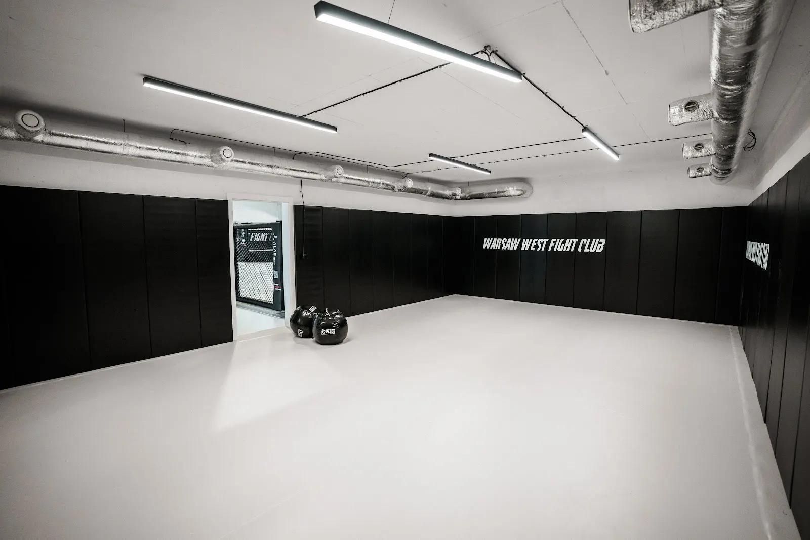 Czarne maty ścienne wokół całej sali z napisem Warsaw West Fight Club i białą matą podłogową