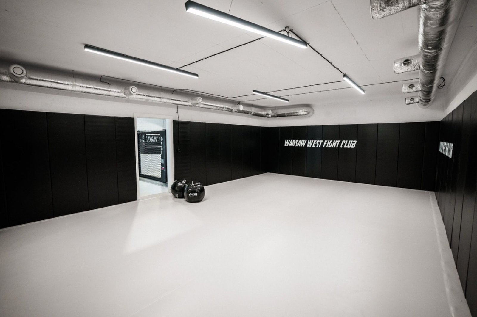 Kameralna sala Warsaw West Fight Club z jasną matą i czarnymi matami ściennymi