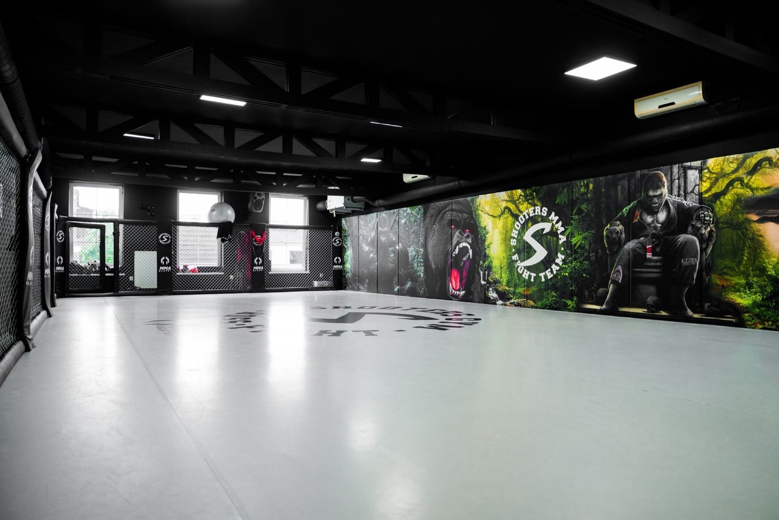 Główna sala Shooters Gym z centralnym logo klubu, ścianą Cage Wall i muralami dżungli