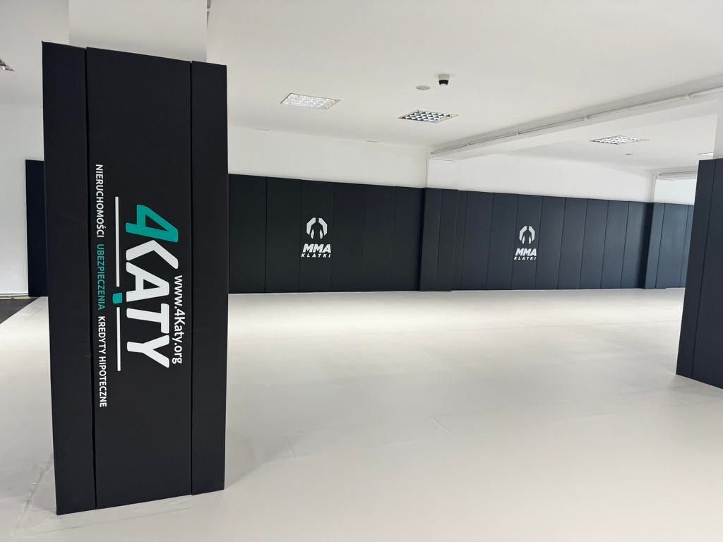 Czarne maty ścienne z białymi logotypami i obłożony słup z nadrukiem sponsora 4Katy, biała podłoga