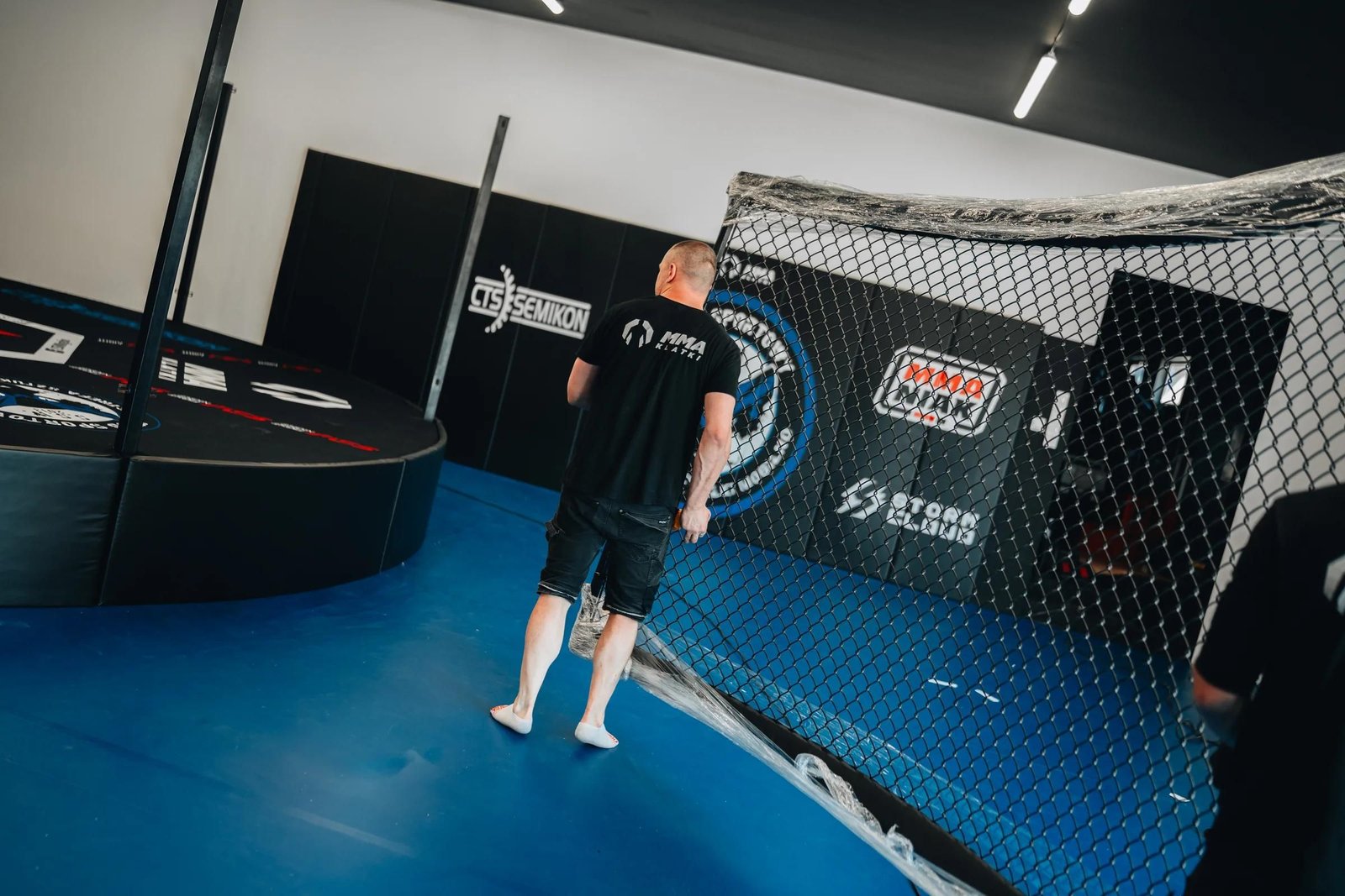 Klatka MMA Juranda po serwisie: nowe siatki i poduszki boczne, zewnętrzna strona klatki zabezpieczona matami ściennymi