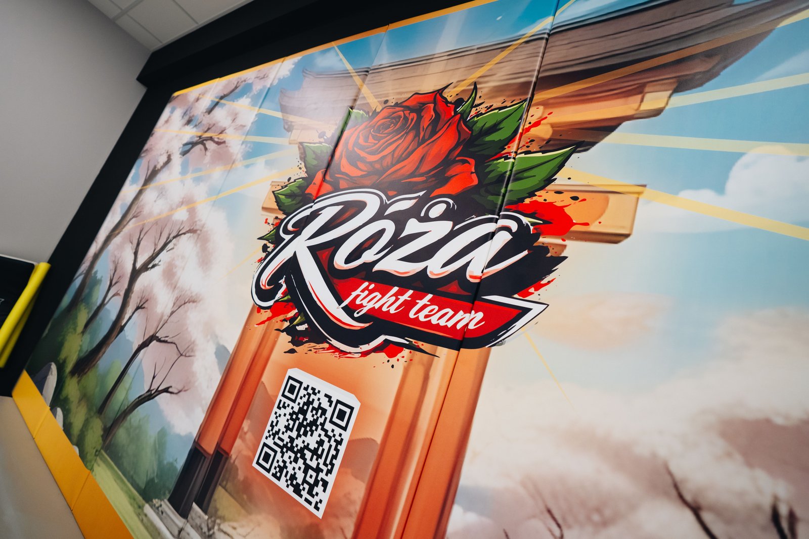 Zbliżenie logo Róża Fight Team i kodu QR na personalizowanej macie ściennej z japońskim motywem.