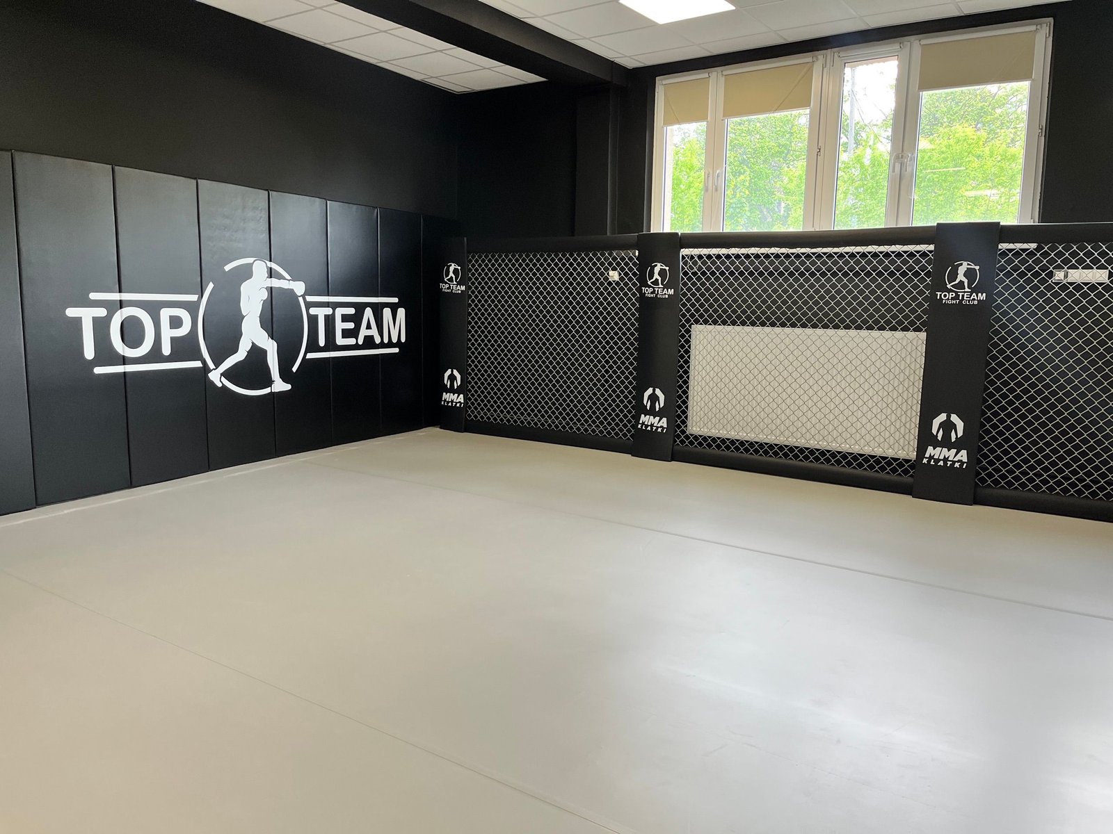 Czarne maty ścienne z logo Top Team i ściana Cage Wall z szarą siatką
