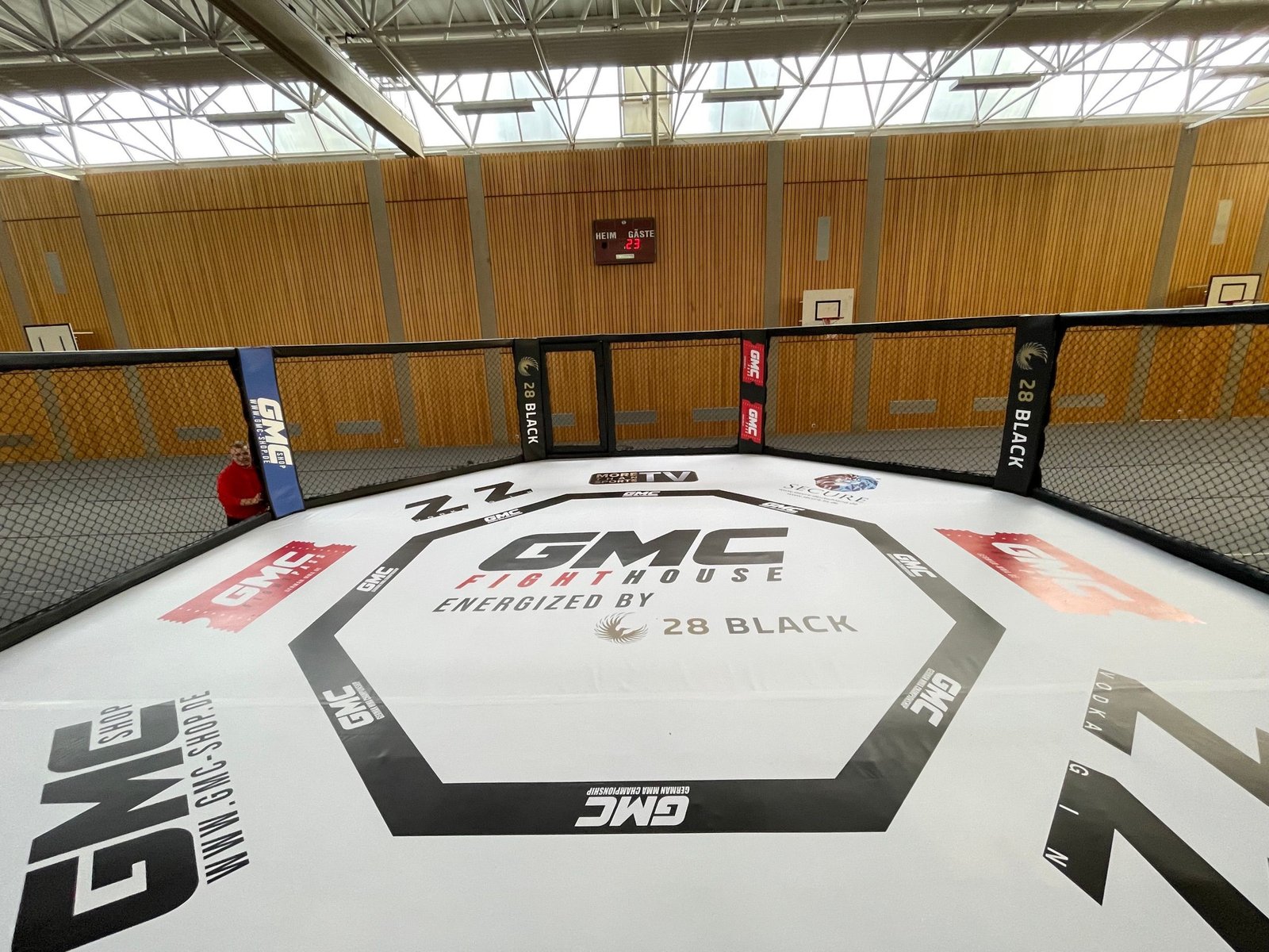 Klatka MMA z matą GMC Fight House ustawiona w hali sportowej