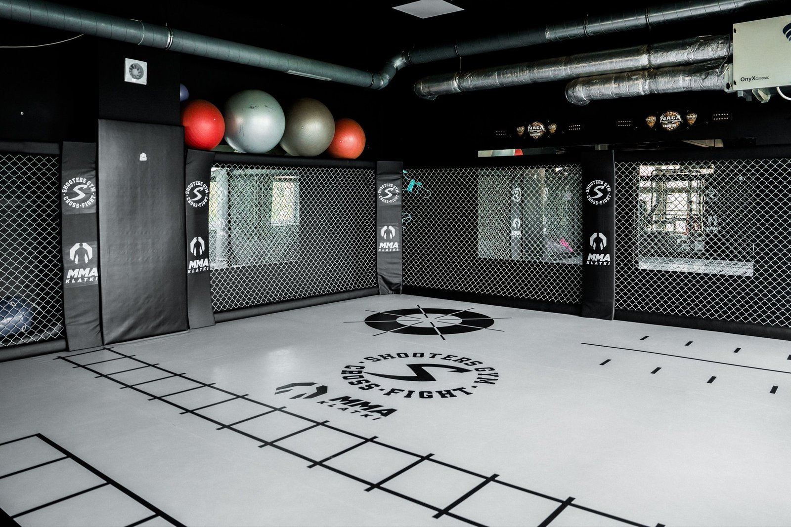 Plansze do treningu footwork nadrukowane na jasnej macie przy ścianach Cage Wall