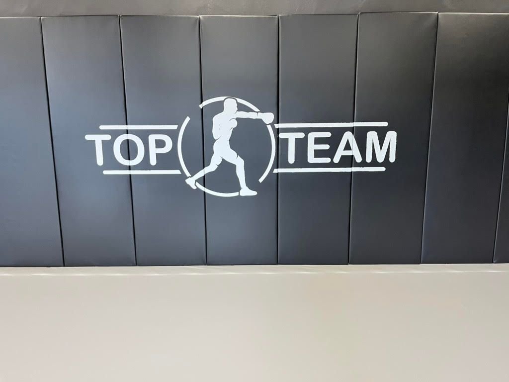 Grafitowe maty ścienne z białym logo Top Team z sylwetką boksera i jasna podłoga