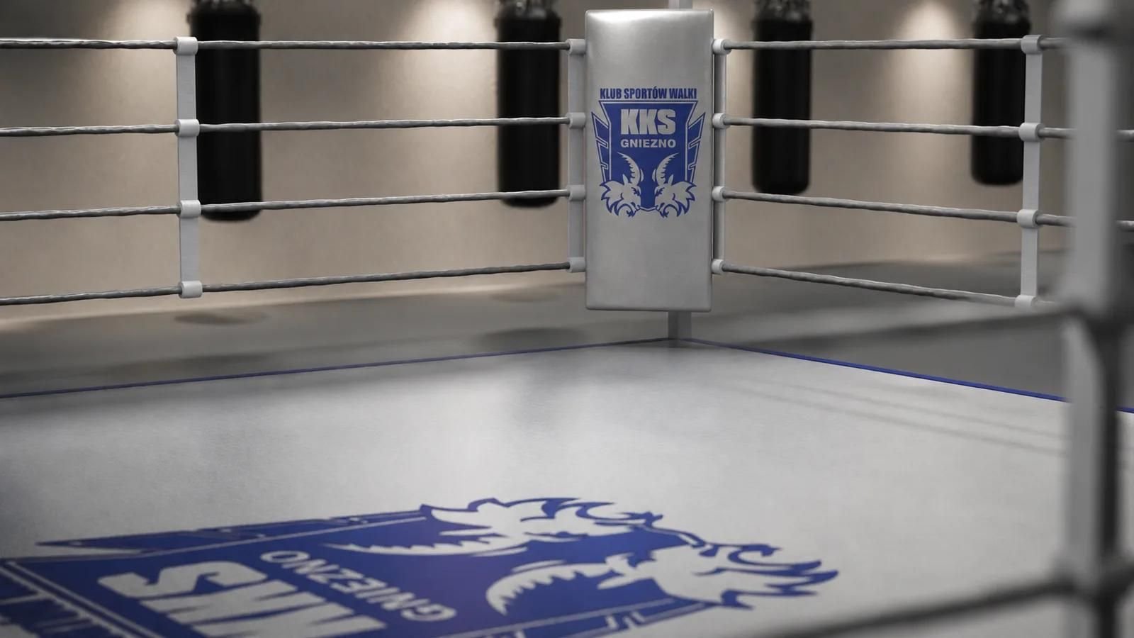 Wizualizacja 3D ringu bokserskiego z bliska: szare liny, poduszka narożnika z logo KKS Gniezno i duży nadruk herbu klubu na macie